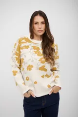 Buzo de tejido de punto con diseño estampado de flores en tonos mostaza y gris sobre fondo blanco. Presenta cuello redondo, mangas largas y corte recto.