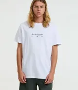 Remera masculina color blanco, modelo Comfort, de manga corta y cuello redondo. Presenta una pequeña estampa frontal con texto y una estampa grande de palmeras en la espalda.