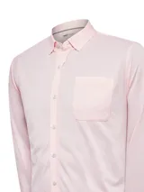 Camisa de manga larga con cuello camisero y cierre frontal de botones. Presenta un bolsillo aplicado en el pecho y un diseño de tejido tipo jersey, ofreciendo un calce regular y cómodo.