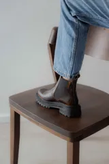 Botas tipo Chelsea de cuero con acabado vintage, diseño de caña media con paneles elásticos laterales y suela track robusta.