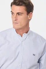 Camisa celeste a rayas verticales, de corte clásico, con cuello mao y manga larga.