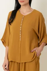 Conjunto de dos piezas compuesto por una blusa de manga corta con cierre frontal de botones y un pantalón ancho de corte holgado con cintura elástica.