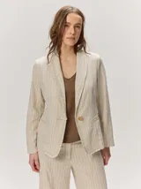 Blazer de lino color negro con pespuntes en contraste de hilo tostado, cuello solapa amplia, cierre frontal con un botón de madera y bolsillos aplicados.