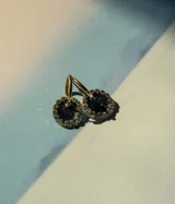 Aros de acero quirúrgico con dije circular de resina rosa y borde de strass dorados.