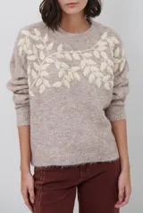 Buzo de tejido de punto en color beige, con cuello redondo y mangas largas. Presenta un delicado bordado de ramas y hojas en color crema en la parte superior del frente.