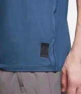 Remera deportiva de hombre con tecnología dry fit, cuello redondo y manga corta. Presenta un diseño liso en color beige con una pequeña etiqueta decorativa en el dobladillo.