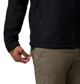 Chaqueta softshell negra con capucha desmontable, cierre frontal completo y bolsillos con cremallera. Presenta logo de la marca bordado en el pecho y puños ajustables.