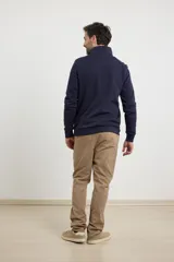 Cardigan de tejido de punto color verde militar, con cierre frontal de metal y cuello redondo. Presenta detalle de tejido plano en la cartera del cierre y en los bolsillos laterales.