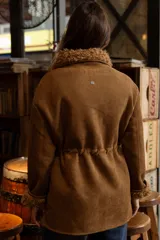 Campera de efecto gamuza color tostado con interior de corderito sintético. Presenta cierre frontal, bolsillos delanteros con solapa, cintura ajustable con cordón y puños con detalle de corderito.