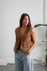 Chaleco de gamuza color marrón con bordados florales en tono oscuro y cierre frontal mediante lazos.