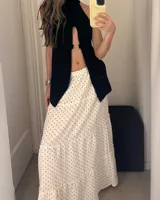 Falda larga de color blanco con estampado de lunares negros, de corte amplio y con volados.