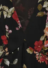 Vestido midi de gasa con estampado floral sobre fondo negro, cuello en pico y mangas largas abullonadas. Presenta un diseño evasé con forro interior y cierre de cremallera lateral.