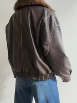 Campera estilo bomber de efecto cuero en color chocolate, con cuello de pelo sintético desmontable, cierre frontal, bolsillos laterales amplios y cintura elástica con ajuste lateral.