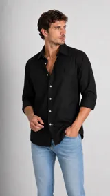 Camisa de manga larga color negro con cuello italiano y cierre frontal de botones. Presenta un pequeño logo bordado en el pecho.