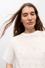Remera blanca de manga corta con tejido de broderie, cuello redondo y diseño holgado.