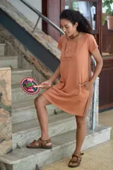 Vestido corto color salmón con paneles laterales en marrón. Cuenta con doble escote para facilitar la lactancia, bolsillos laterales y bajos redondeados.