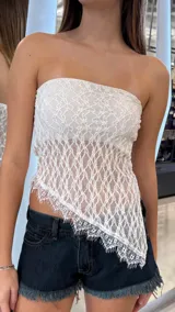 Top strapless de encaje blanco con diseño asimétrico en el ruedo y terminaciones desflecadas.
