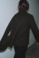 Jersey de lana con cuello subido, manga larga y bajo asimétrico con detalle de nudo lateral. Presenta acabados en rib en cuello, puños y ruedo.