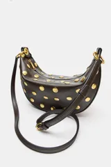 Bolso tipo hobo color marrón oscuro con tachas doradas distribuidas por todo el cuerpo. Cuenta con un asa de hombro y dos anillas metálicas doradas. El cierre es de cremallera metálica y tiene un bolsillo interior con cremallera.