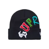 Gorro beanie negro con vuelta, confeccionado en tejido de punto acanalado, con letras bordadas en colores rojo, verde, celeste y blanco en la parte frontal, y logo de New Era en el lateral.