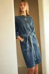 Trench de jean elastizado azul con cierre delantero, frunce en la cintura y lazo para atar.