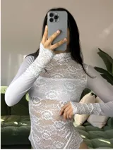 Body de encaje blanco con cuello alto y mangas largas de microtul. Presenta un diseño entallado con detalles de puntilla en los puños y en el borde inferior, combinando transparencias y texturas delicadas.