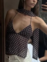Top marrón con estampado de lunares blancos, escote halter y tiras finas. Incluye una tira de tela que se ata al cuello.