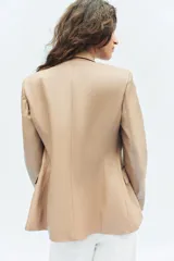 Blazer cruzado de efecto piel color bordó, con solapas de muesca, mangas largas y bolsillos con solapa en la parte delantera. Cierre frontal con botones a tono.