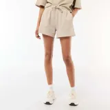 Short de felpa beige de corte holgado, con cintura elástica ajustable mediante cordón y bolsillos laterales.