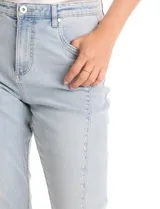 Jean de tiro alto con corte bootcut, confeccionado en denim de lavado claro. Presenta cierre frontal con botón, bolsillos funcionales y detalle de pespuntes verticales con aplicación de tachas a lo largo de las piernas.