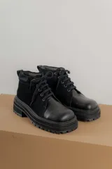 Borcegos de punta cuadrada con diseño acordonado, combinando paneles de cuero texturizado y gamuza en tonos marrones. Presentan una suela track gruesa de goma negra y cordones negros.