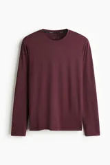 Remera deportiva de manga larga color bordó, con cuello redondo y tejido funcional con textura microperforada.