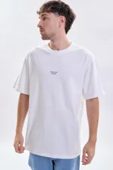 Remera de corte oversize color blanco, con cuello redondo y estampa pequeña con texto en el centro del pecho.