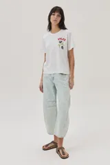 Remera blanca de algodón con cuello redondo y mangas cortas. Estampado en el frente con la palabra "Dolce" en rojo y un diseño floral en negro y verde.