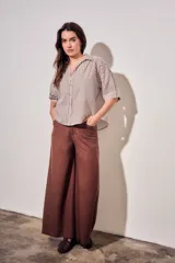 Camisa de corte oversize con estampado de rayas verticales en tonos marrón y beige. Presenta cuello camisero, cierre frontal con botones y mangas cortas con caída relajada.