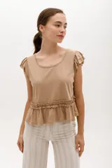 Remera de algodón y lyocell color beige, con cuello redondo, mangas cortas con volados y detalle de frunce con volado en la cintura.