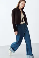 Jeans de tiro alto con corte wide leg, confeccionados en denim azul. Presentan diseño de cinco bolsillos, cierre frontal con cremallera y botón, y bajo con vuelta ancha.