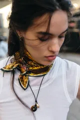Pañuelo cuadrado de tejido satinado con estampado floral y botánico en tonos marrones, violetas y amarillos. Presenta un borde con línea a contraste.