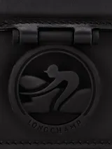 Cartera tipo shoulder bag de cuero liso color negro, con solapa frontal y cierre metálico con logo grabado. Posee una correa ajustable para llevar al hombro.
