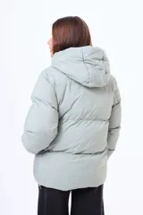 Campera puffer de corte holgado en color beige, con capucha integrada, cierre frontal completo y bolsillos laterales. Presenta un diseño acolchado con acabado mate y puños elásticos.
