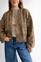 Campera bomber de corte oversize con cierre frontal metálico, mangas globo y diseño con bordados florales en toda la superficie.