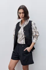 Short de tiro alto confeccionado en algodón, con calce relajado y silueta recta. Presenta pinzas delanteras, bolsillos laterales y botones decorativos en la cintura.