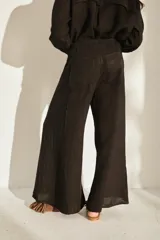 Pantalón ancho negro de lino con cintura elástica y detalles de flecos en los laterales.