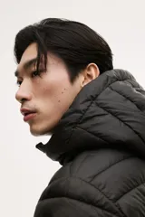 Campera puffer liviana color verde militar, con cuello elevado, capucha y cierre frontal. Incluye bolsillos laterales con cierre y bolsillos interiores abiertos. Diseño guateado y corte ajustado.