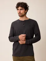 Remera de manga larga con cuello redondo y cierre frontal parcial con botones. Presenta un diseño de color sólido con un pequeño logo bordado en el pecho.