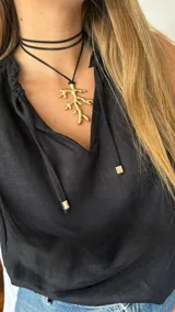 Collar con cordón marrón y dije dorado en forma de rama.