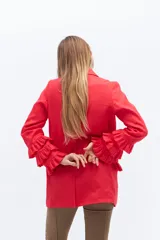 Blazer color beige confeccionado en lino, con cuello solapa, cierre frontal con un botón y mangas largas con volantes en capas.