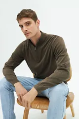 Buzo de punto color verde oliva con medio cierre frontal, cuello alto y logo bordado.