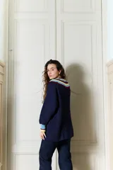 Buzo de punto bordó estilo oversize, con cuello babero amplio con volados y franjas en tonos amarillo y rojo, manga larga con terminación en volados.