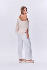 Poncho de tejido de punto color beige, con cuello amplio y terminación con flecos.